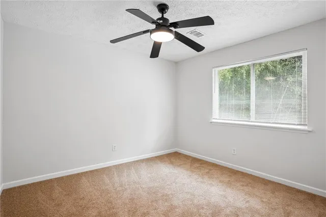an empty room with a window and a fan