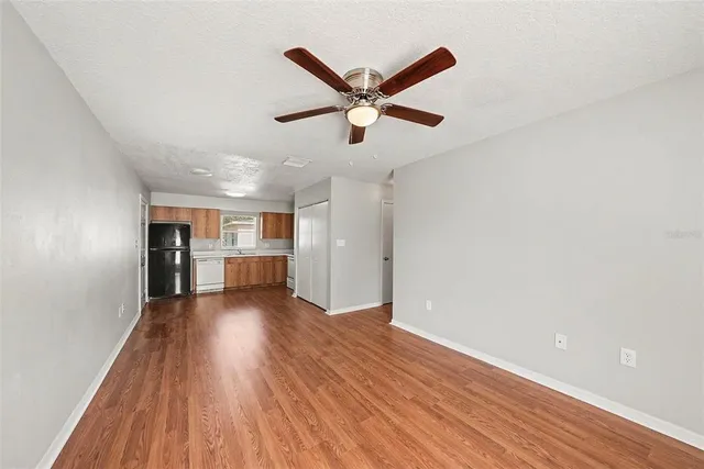 a view of empty room with wooden floor and ceiling fan