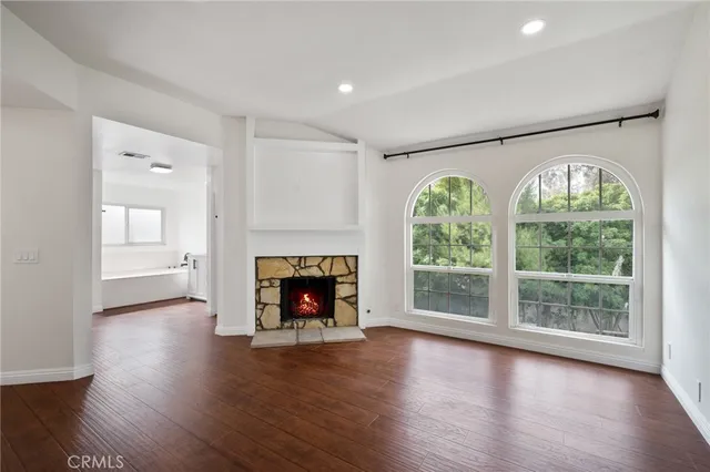 an empty room with wooden floor a fireplace and a large window