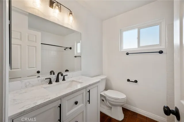 a bathroom with a granite countertop sink a toilet and a mirror