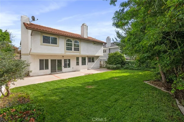 a view of house with a big yard potted plants and large tree