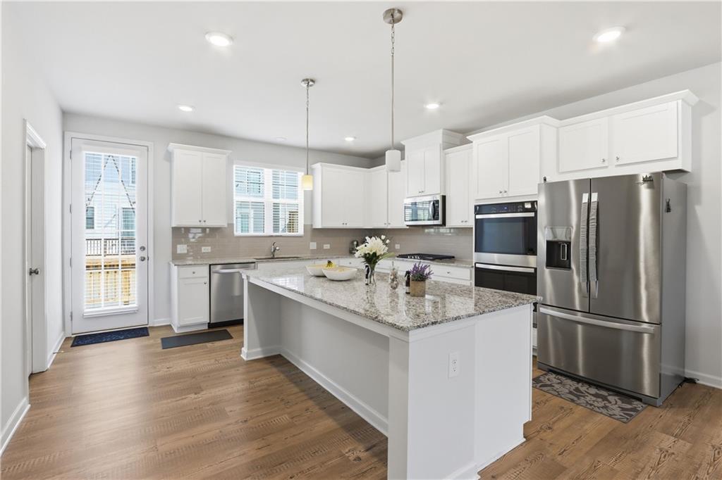 3535 Senna Road Duluth, GA 30096 - Photo 40 of 60 a kitchen with stainless steel appliances granite countertop a refrigerator a sink dishwasher a stove and white cabinets with wooden floor