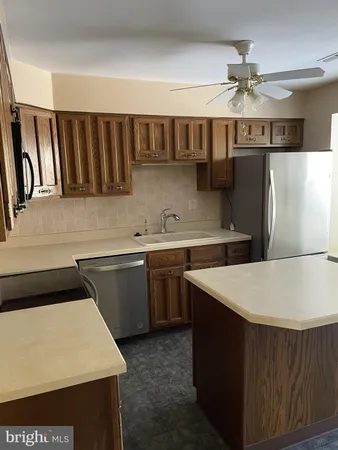 a kitchen with a sink dishwasher a stove and a refrigerator with wooden cabinets