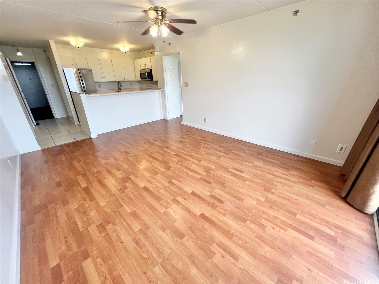 98-402 Koauka Loop, Unit 2113 Aiea, HI 96701 - Photo 2 of 7 a view of a kitchen with wooden floor and a ceiling fan