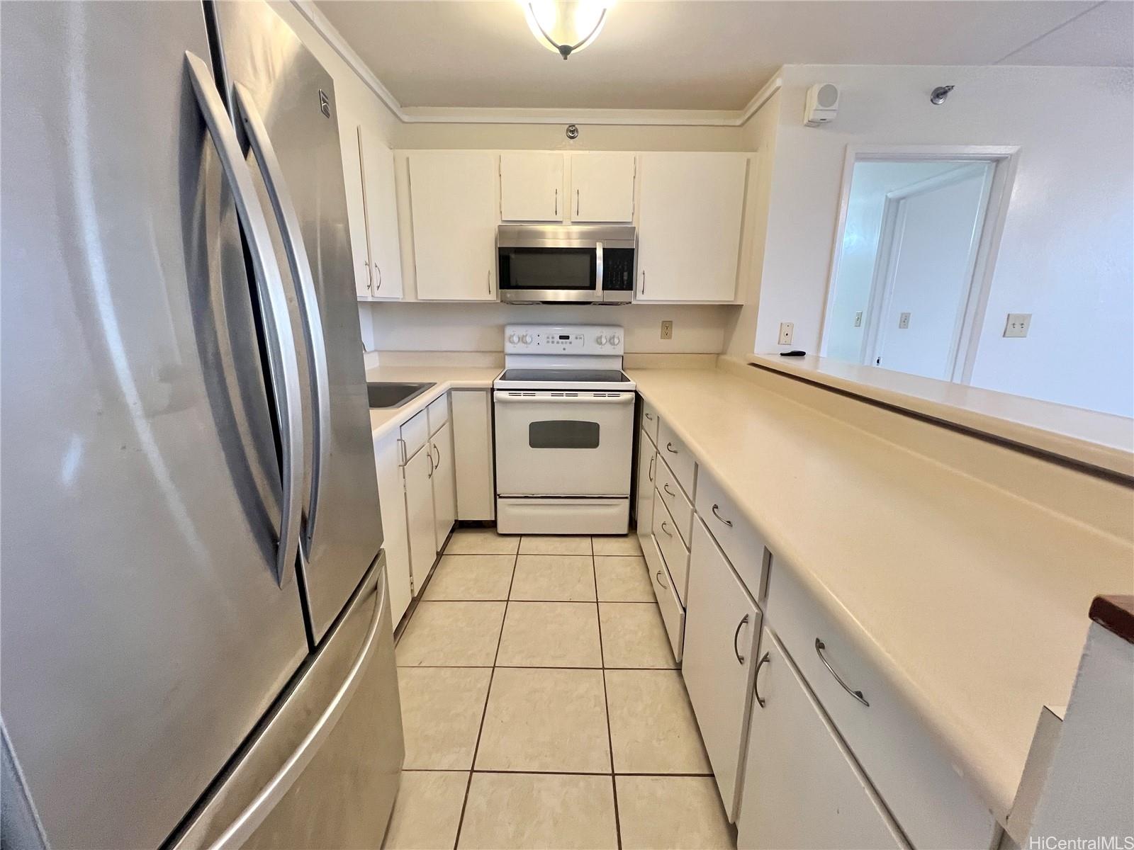 98-402 Koauka Loop, Unit 2113 Aiea, HI 96701 - Photo 3 of 7 a kitchen with a sink a microwave a refrigerator and cabinets