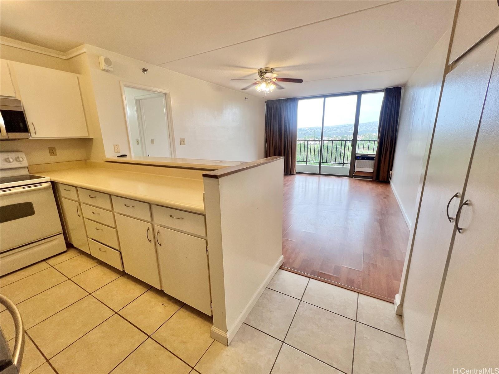 98-402 Koauka Loop, Unit 2113 Aiea, HI 96701 - Photo 4 of 7 a view of a kitchen with fridge and wooden floor