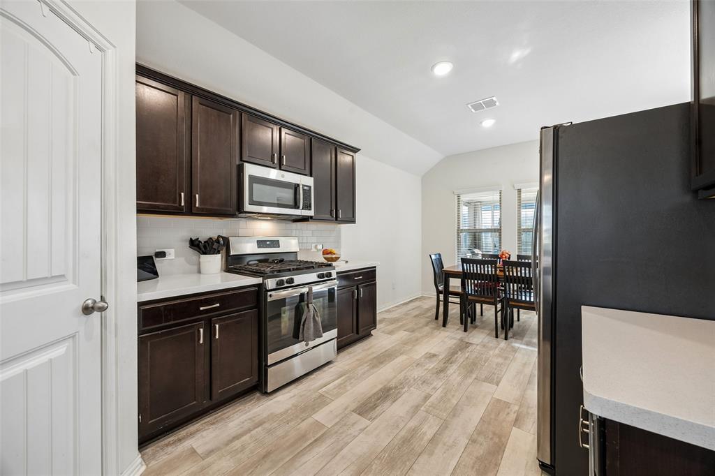 406 Madrone Lane Princeton, TX 75407 - Photo 7 of 30 Kitchen featuring dark wood cabinetry, light countertops, stainless steel appliances, and wood-finish flooring
