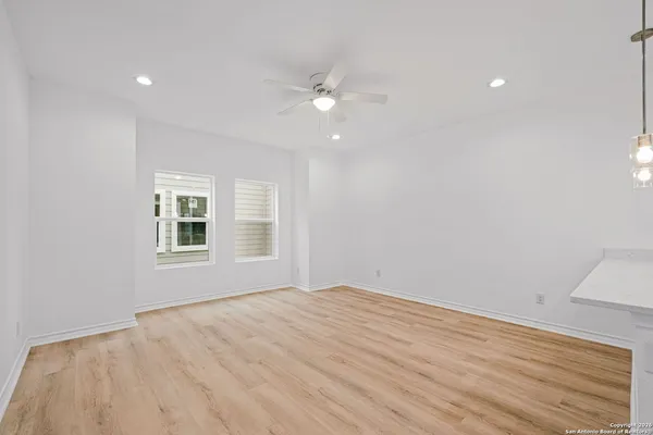 a view of empty room with wooden floor and fan