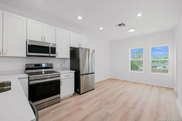 a kitchen with a stove a microwave and white cabinets