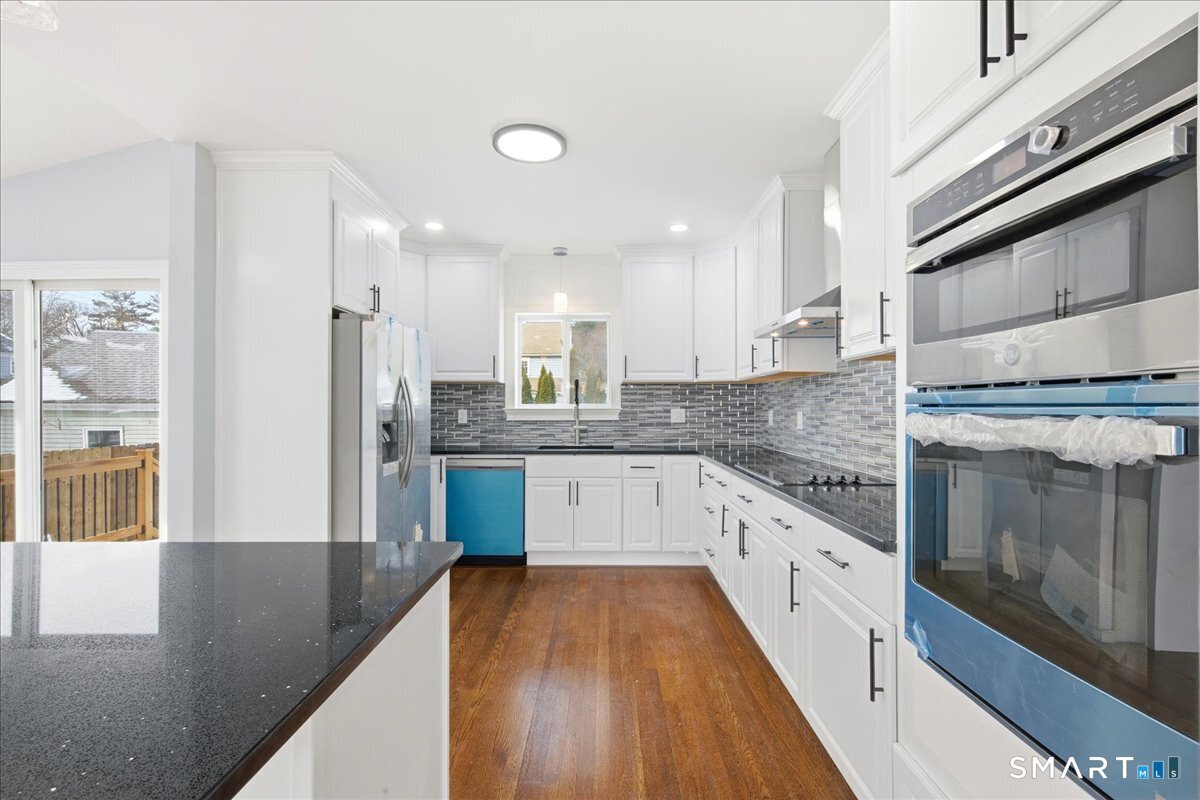 52 Coram Street Hamden, CT 06517 - Photo 15 of 40 a large kitchen with stainless steel appliances kitchen island granite countertop a stove a sink and a granite counter tops with white cabinets