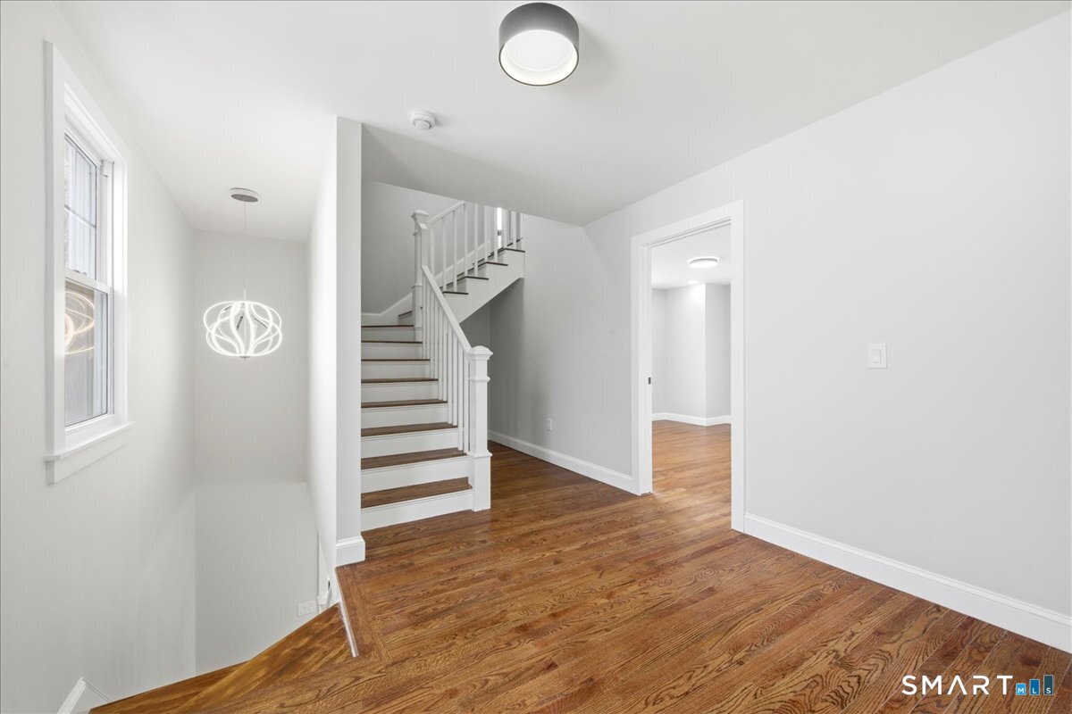 52 Coram Street Hamden, CT 06517 - Photo 25 of 40 an empty room with wooden floor and stairs
