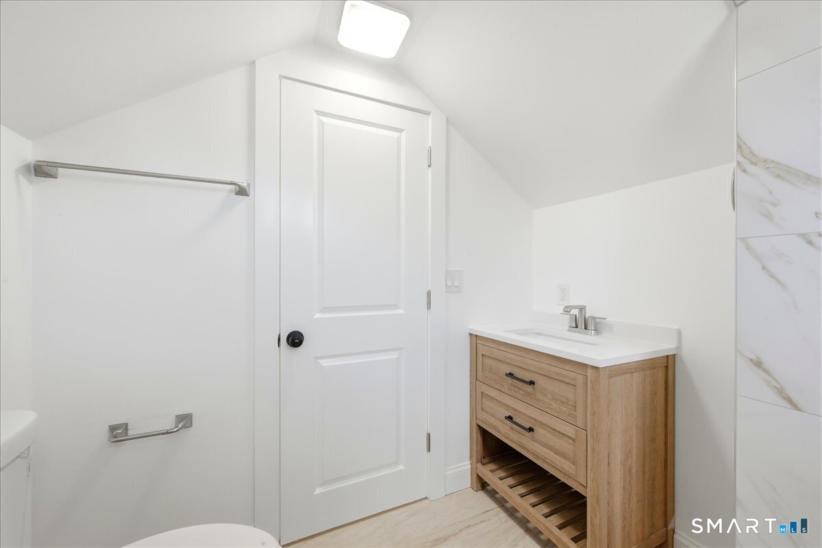 52 Coram Street Hamden, CT 06517 - Photo 36 of 40 a bathroom with a toilet a sink a vanity and mirror