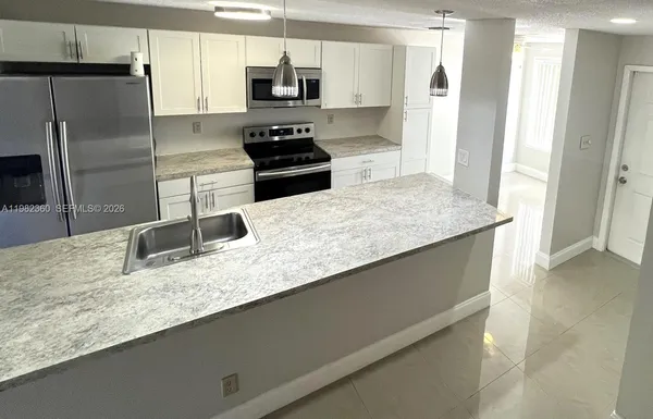 a kitchen with stainless steel appliances granite countertop a refrigerator a stove and a sink with wooden floor