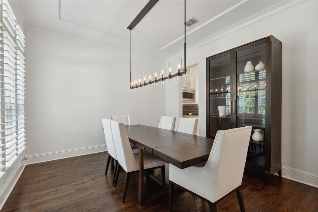 12444 Riverhill Road Frisco, TX 75033 - Photo 14 of 37 Dining area with hardwood flooring, crown molding, plantation shutters, and a designer chandelier.