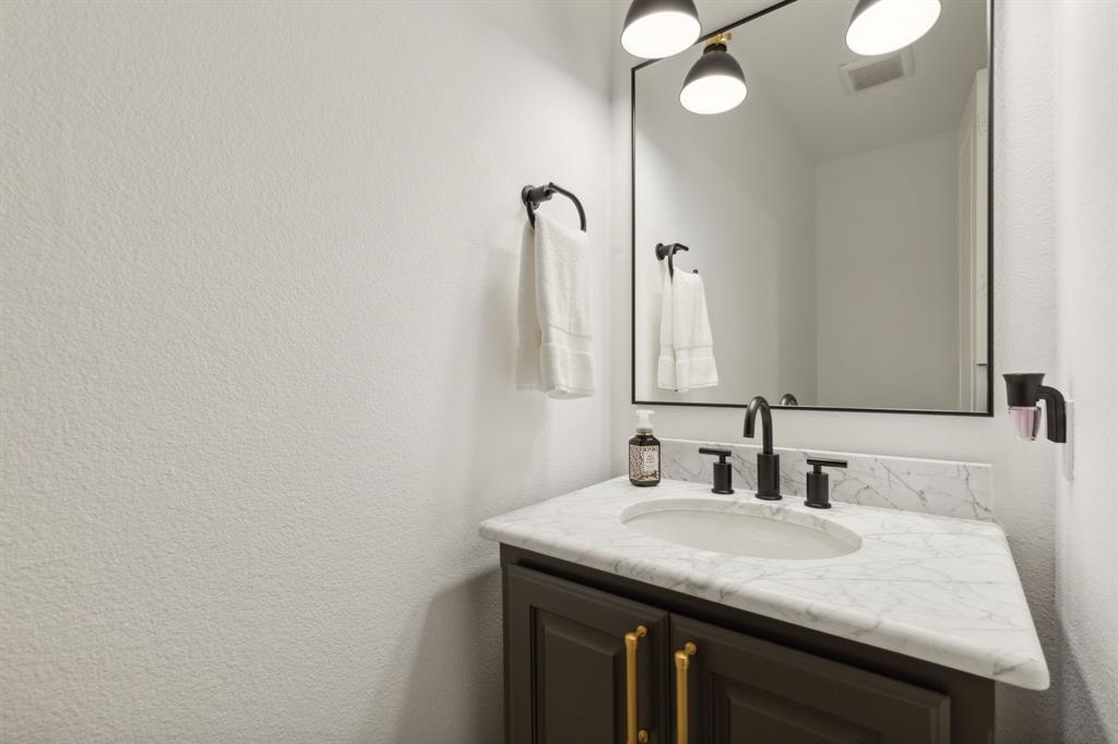 12444 Riverhill Road Frisco, TX 75033 - Photo 17 of 37 Half Bathroom off Family Room featuring large marble vanity, designer lighting and custom mirror.