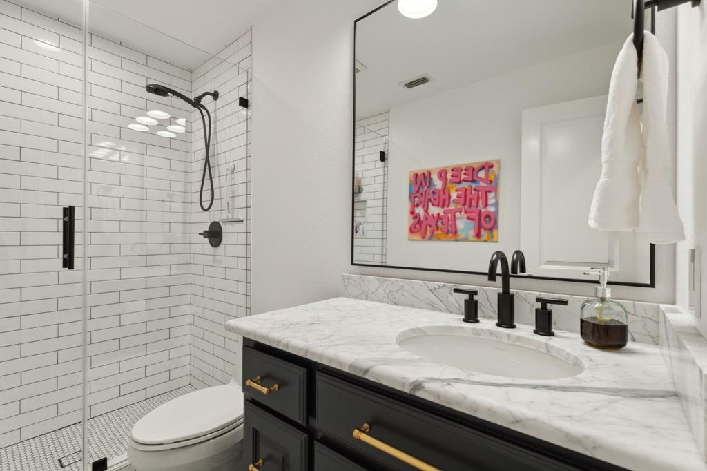 12444 Riverhill Road Frisco, TX 75033 - Photo 28 of 37 Full bathroom with tiled shower, designer lighting, marble vanity with extensive cabinet space, frameless shower glass, and custom mirror.