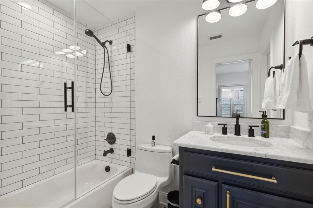 12444 Riverhill Road Frisco, TX 75033 - Photo 30 of 37 Full bathroom with tiled shower/tub with frameless glass enclosure, custom metal wrapped mirror, designer lighting, marble vanity with cabinet base.