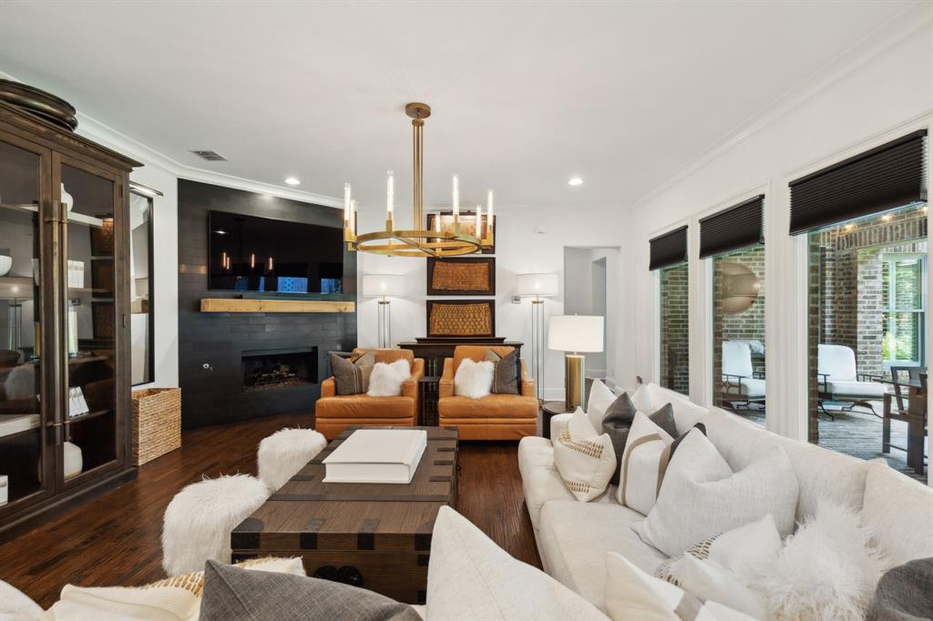 12444 Riverhill Road Frisco, TX 75033 - Photo 9 of 37 Family room with ornamental molding, a gas fireplace, designer lighting, and hardwood floors