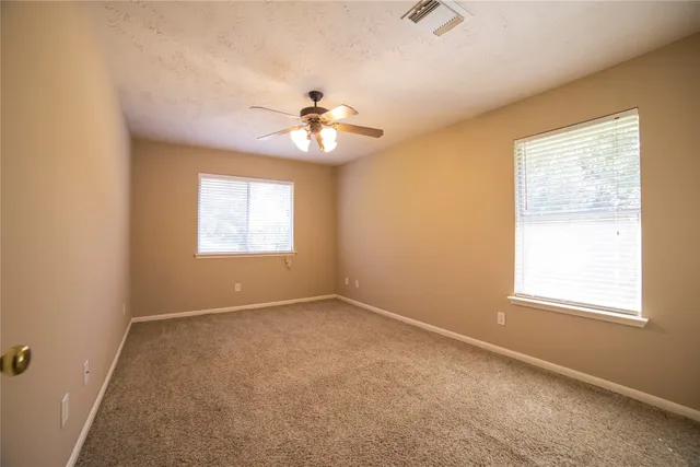 an empty room with windows and fan