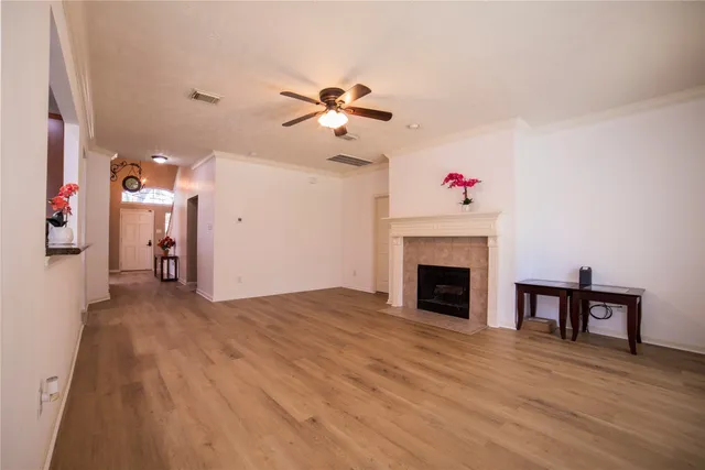 a view of a livingroom with a fireplace a chandelier fan and wooden floor