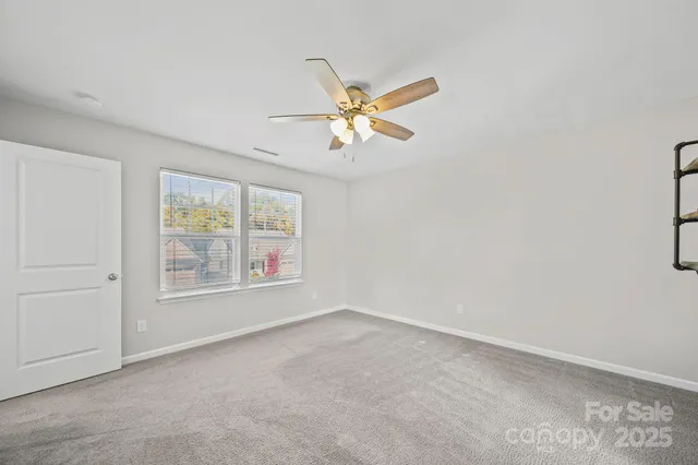 a view of an empty room with window and a fan