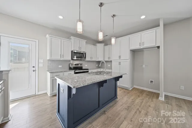 a kitchen with kitchen island granite countertop a sink a stove and cabinets