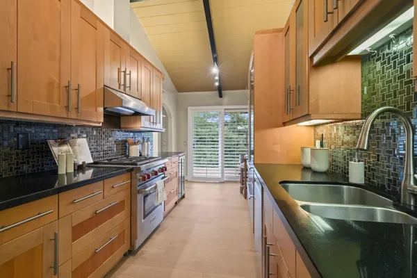 a kitchen with stainless steel appliances granite countertop a sink a stove and a wooden cabinets