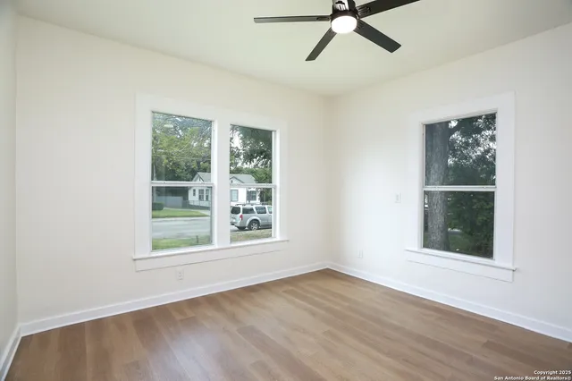 a view of an empty room with a window and wooden floor