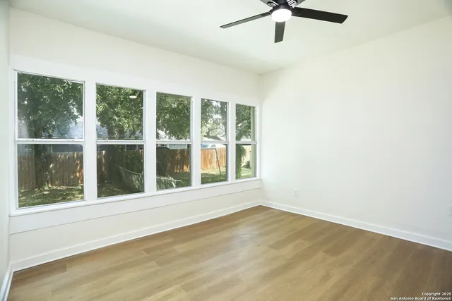 a view of an empty room with a window and wooden floor