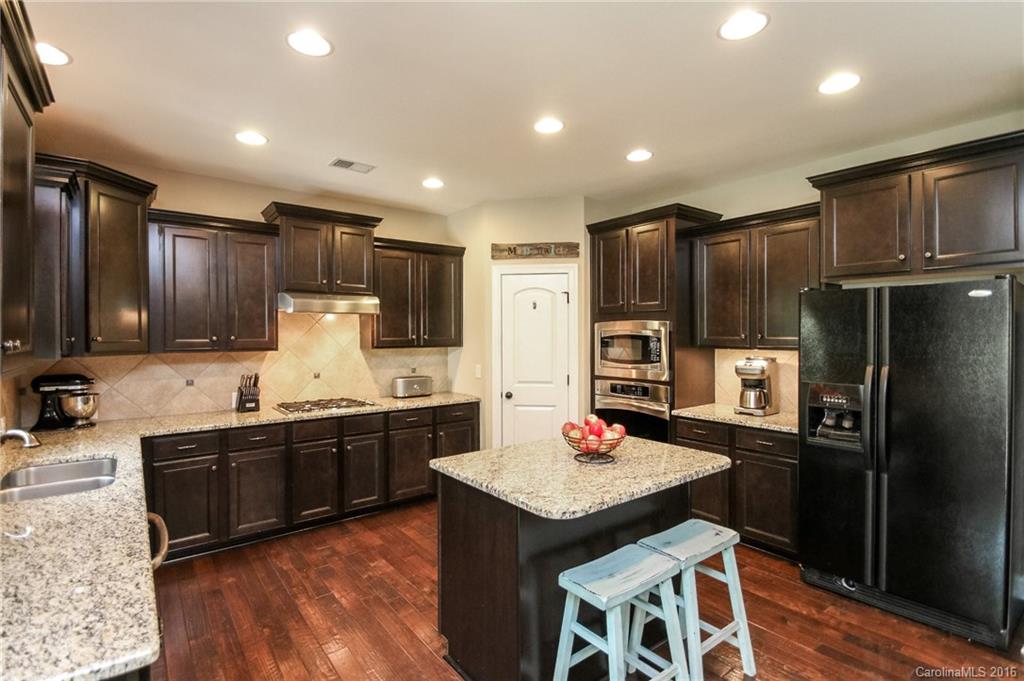 662 Reliance Court, Unit 13 Tega Cay, SC 29708 - Photo 11 of 24 a kitchen with granite countertop stainless steel appliances a sink a stove a refrigerator cabinets and a dining table
