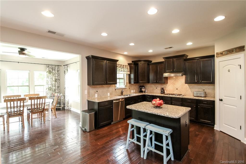662 Reliance Court, Unit 13 Tega Cay, SC 29708 - Photo 10 of 24 a kitchen with stainless steel appliances granite countertop a stove top oven a sink dishwasher a dining table and chairs with wooden floor