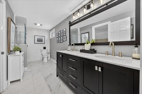 a spacious bathroom with a double vanity sink a mirror and a