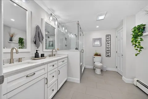 a spacious bathroom with a double vanity sink a large mirror a toilet and a shower