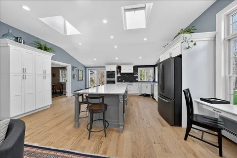 a kitchen with stainless steel appliances refrigerator dining table and chairs