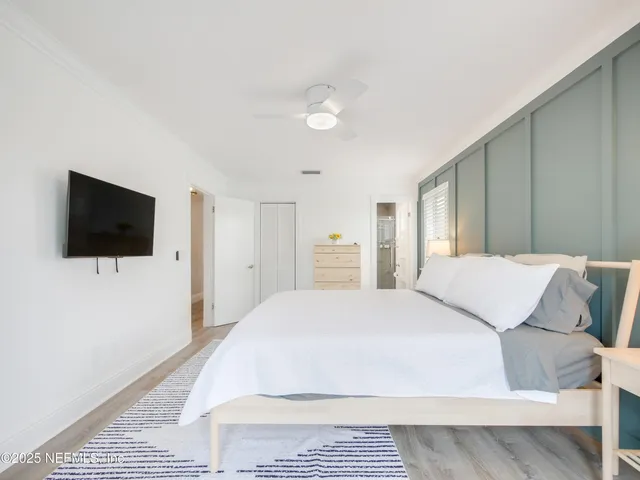 a spacious bedroom with a bed and a flat screen tv