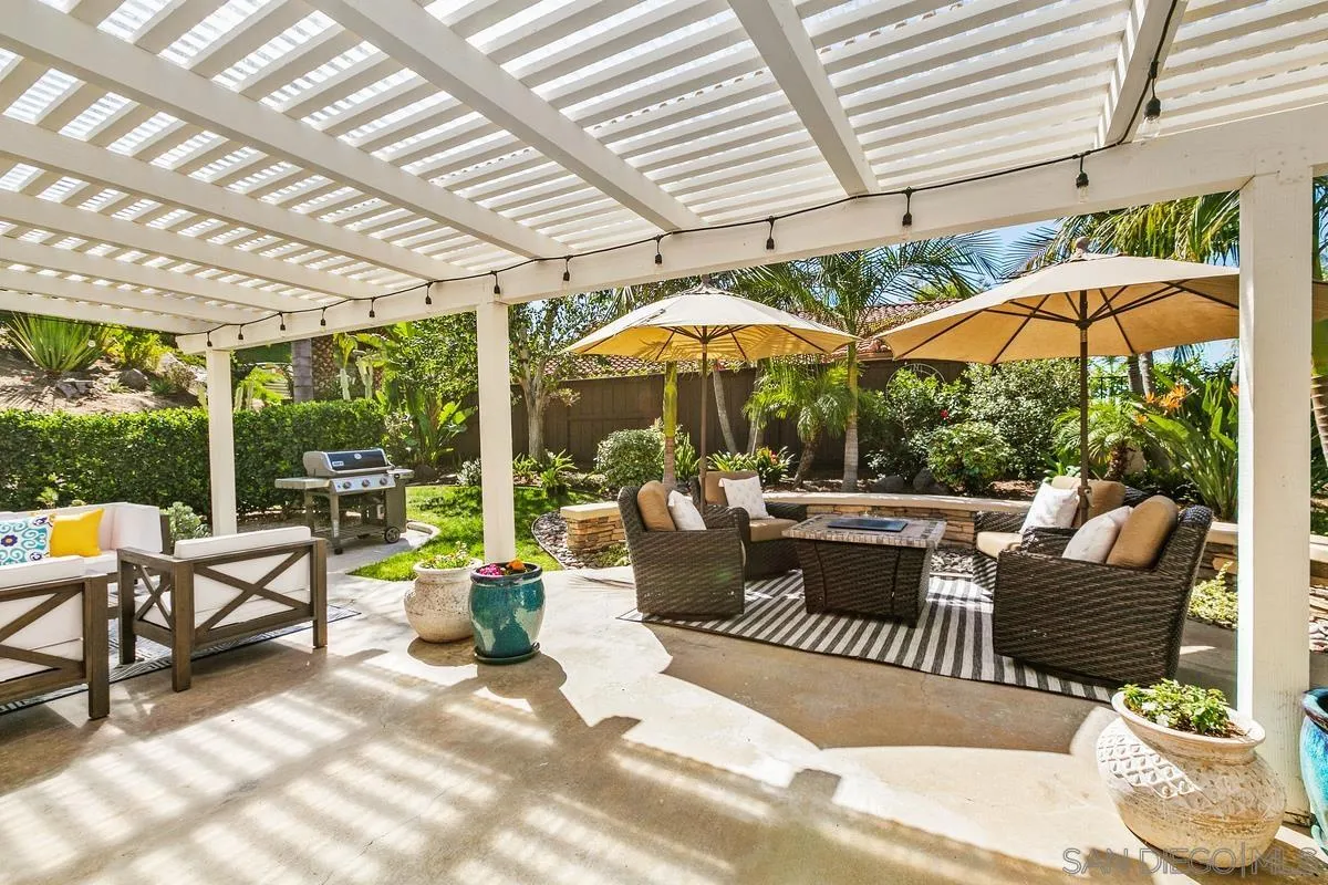 3330 Vista Rocosa Escondido, CA 92029 - Photo 20 of 29 a view of a patio with a dining table and chairs under an umbrella with a small yard