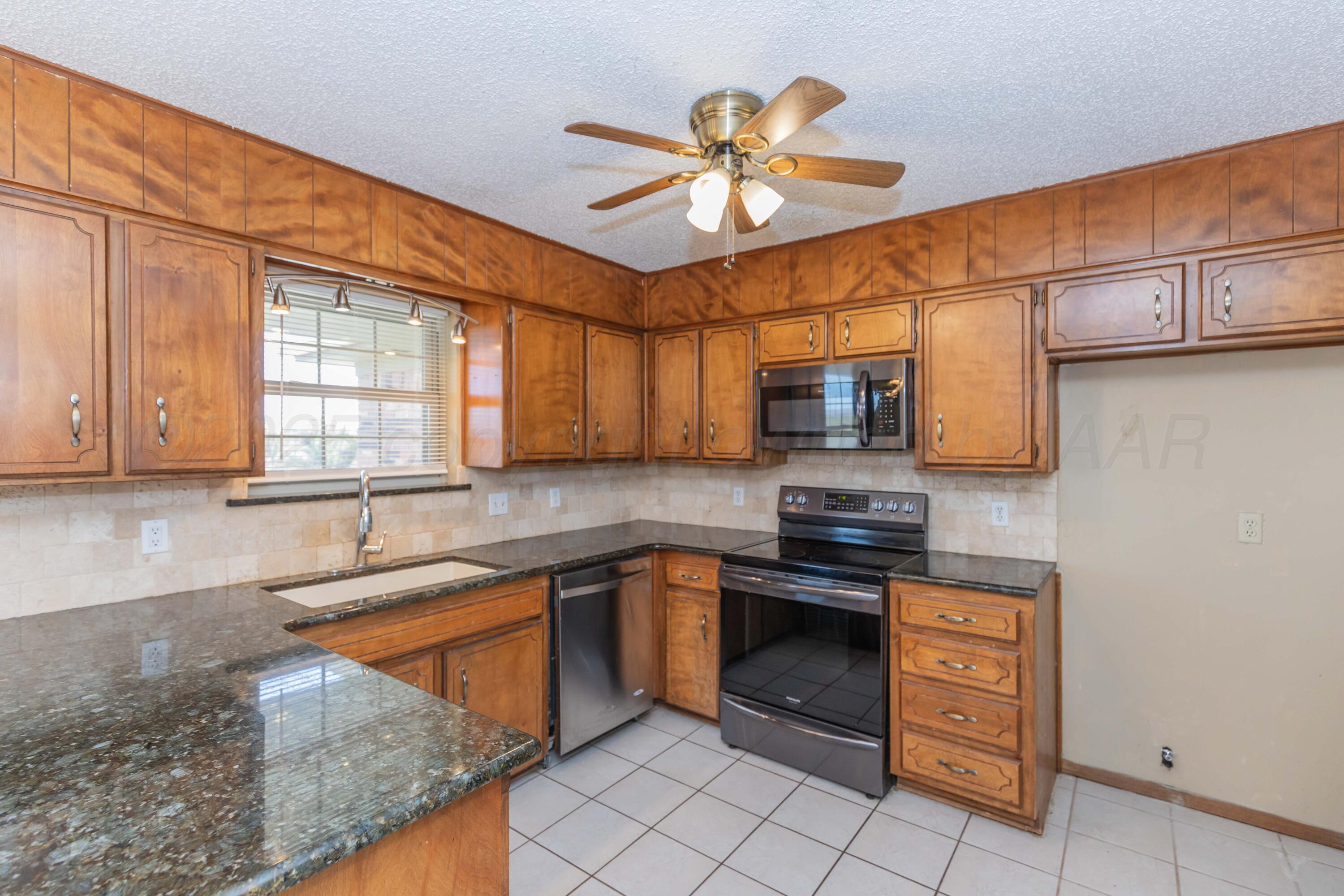 134 Eddie Street Canadian, TX 79014 - Photo 12 of 45 a kitchen with stainless steel appliances granite countertop a sink a stove and a microwave