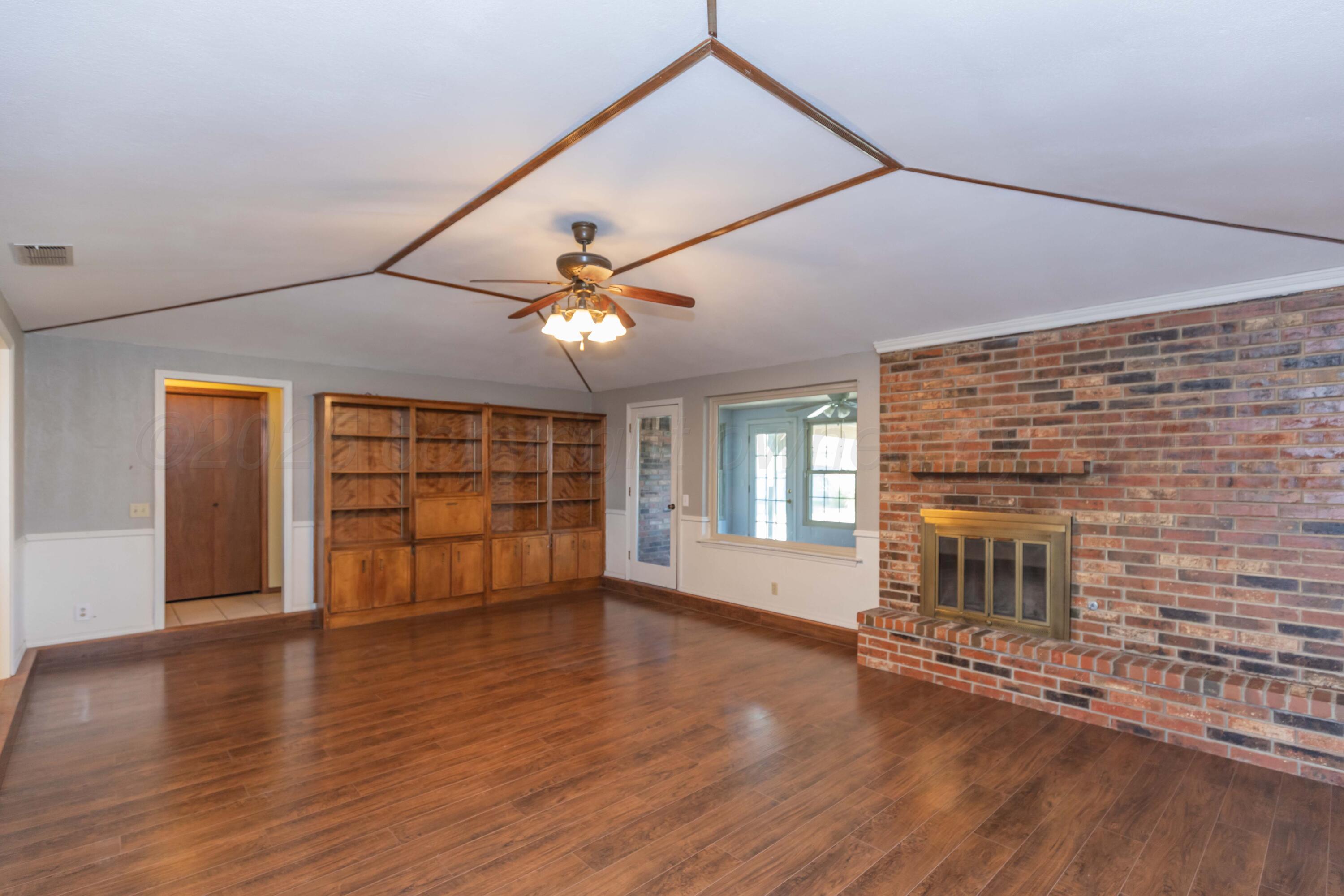 134 Eddie Street Canadian, TX 79014 - Photo 7 of 45 an empty room with wooden floor chandelier and windows