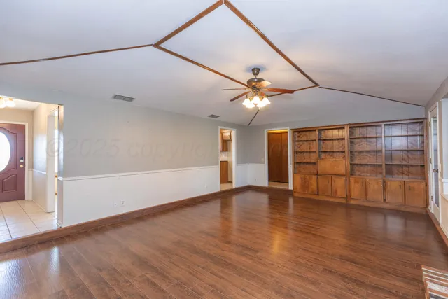 an empty room with wooden floor and windows