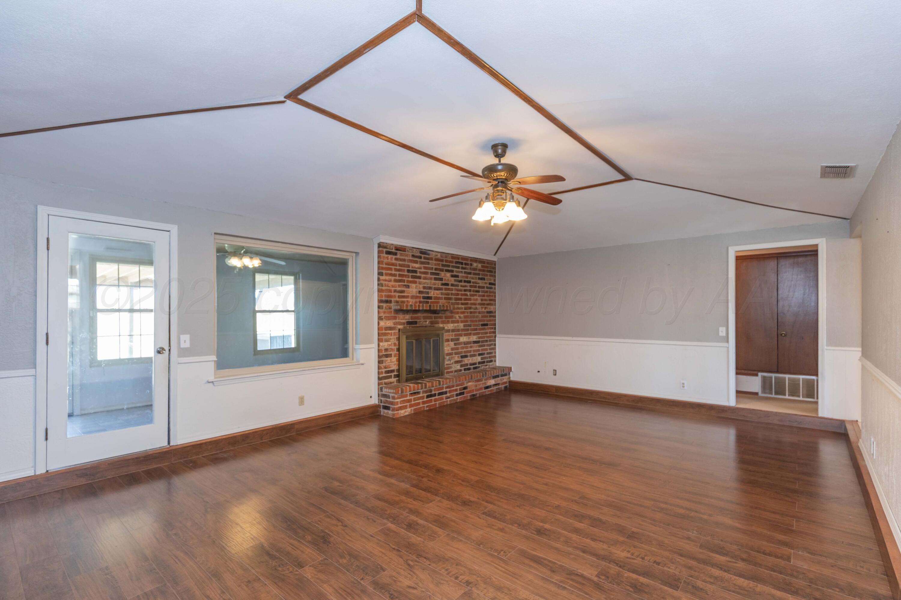 134 Eddie Street Canadian, TX 79014 - Photo 10 of 45 an empty room with wooden floor chandelier fan and windows