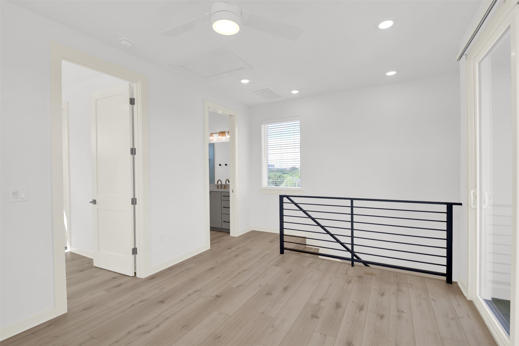 7208 Providence Avenue, Unit 1 Austin, TX 78752 - Photo 20 of 26 The property features light wood flooring, a ceiling fan, recessed lighting, and a modern black railing