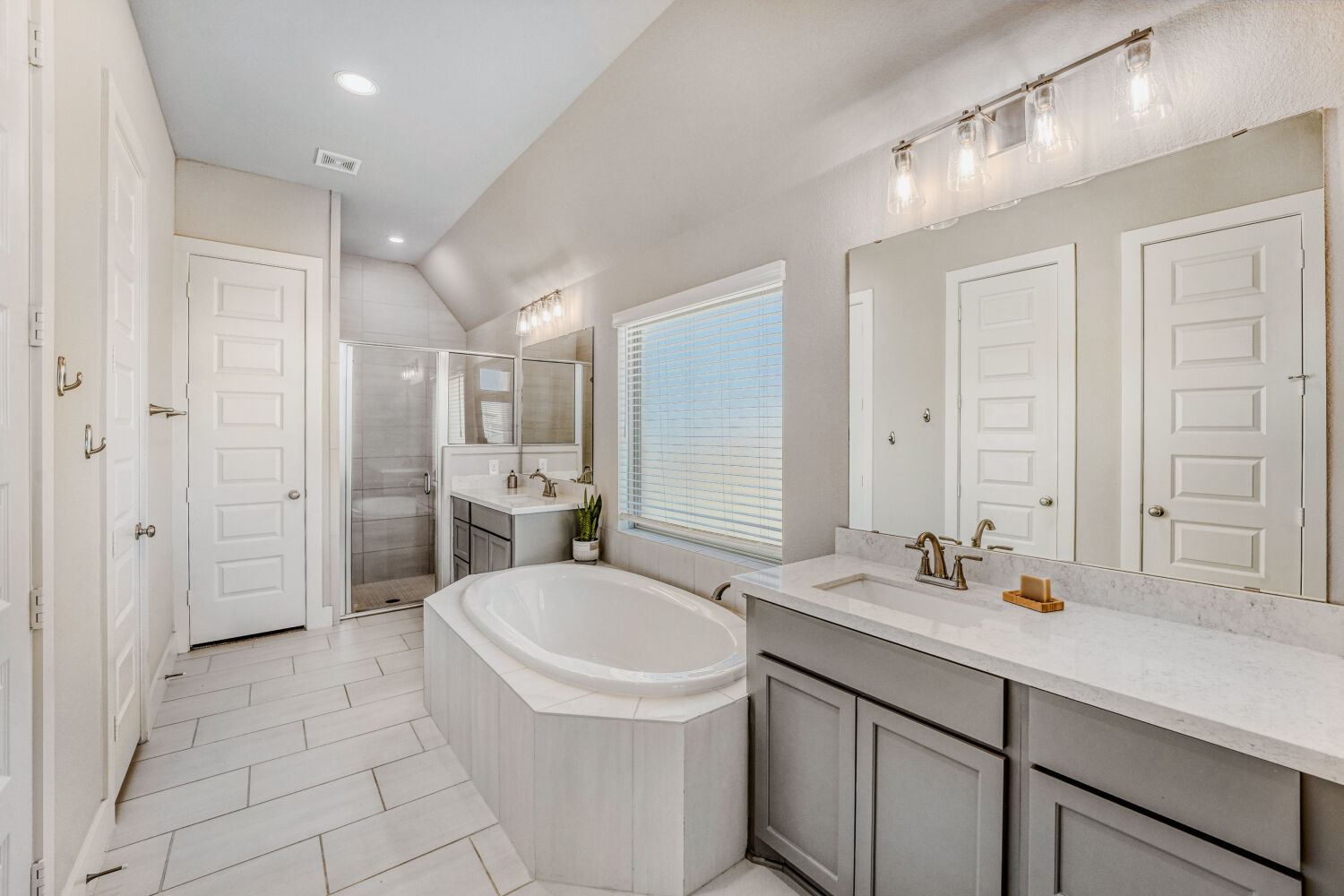 505 Trout River Road Kyle, TX 78640 - Photo 14 of 29 Full bath featuring a stall shower, a bath, two vanities, lofted ceiling, and light tile patterned floors