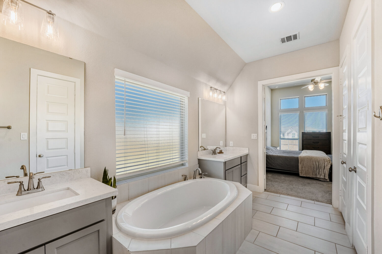 505 Trout River Road Kyle, TX 78640 - Photo 15 of 29 Ensuite bathroom with two vanities, a garden tub, light tile patterned floors, a ceiling fan, and vaulted ceiling