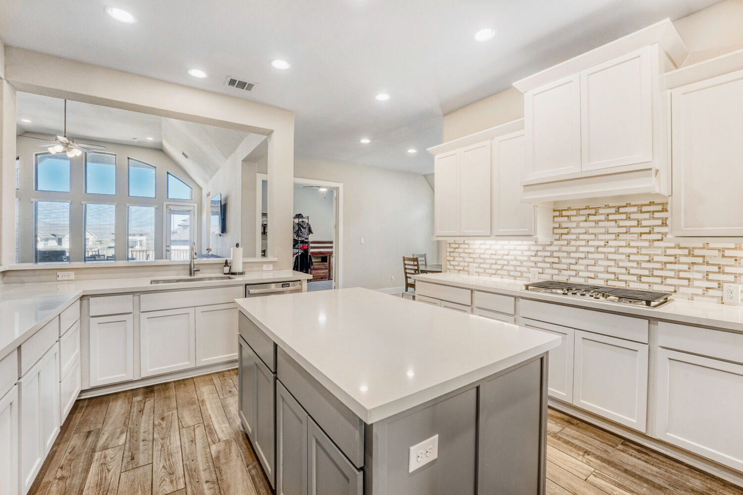 505 Trout River Road Kyle, TX 78640 - Photo 6 of 29 Two tone kitchen with a center island, recessed lighting, ceiling fan, tasteful backsplash, and light stone countertops