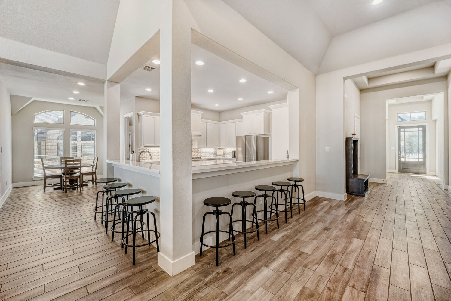 505 Trout River Road Kyle, TX 78640 - Photo 8 of 29 Kitchen featuring light wood finished floors, stainless steel fridge, white cabinetry, recessed lighting, and a kitchen bar