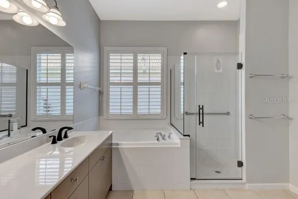 a bathroom with a granite countertop tub sink and mirror