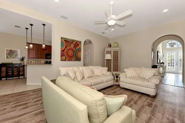 a living room with furniture kitchen view and a chandelier