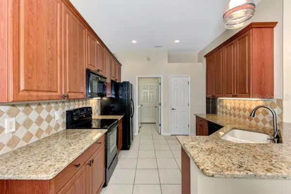 a kitchen with granite countertop a sink a stove and a wooden cabinets