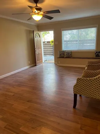 a view of an empty room with wooden floor and a window