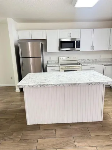 a kitchen with kitchen island a sink a refrigerator and a stove